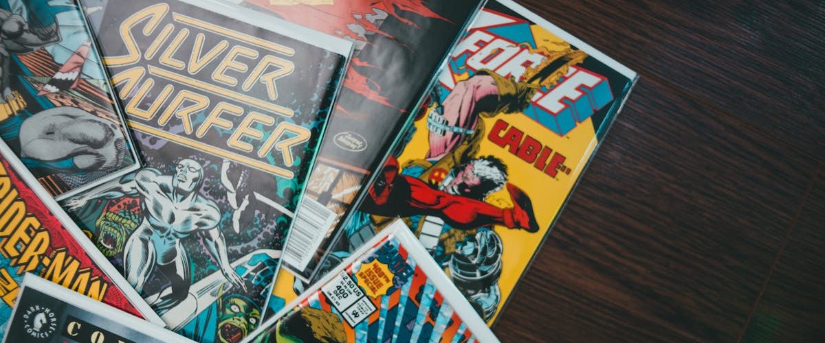 A vibrant assortment of classic comic book covers displayed flat on a wooden surface.